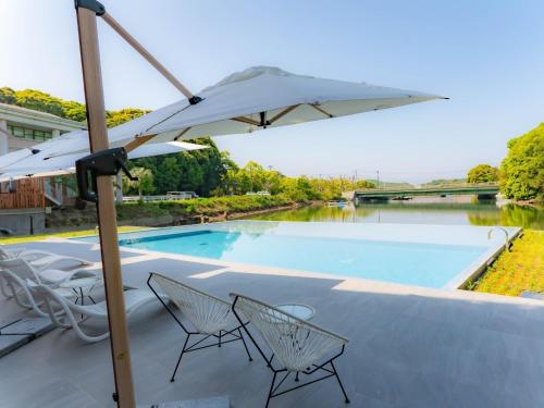 a patio with chairs and an umbrella next to a swimming pool at Hotel Flags Sasebo KujuKusima in Sasebo