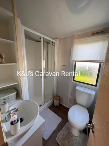 a bathroom with a white toilet and a sink at K&J's Caravan Rental in Kinmel Bay