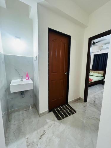 a bathroom with a sink and a brown door at Mangalore serviced flats in Mangalore