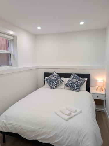 a bedroom with a white bed with two towels on it at Modern 2BR Suite Steps to SkyTrain in Vancouver