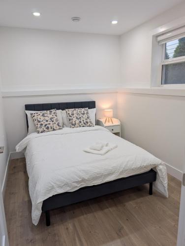 a bedroom with a large white bed with a window at Modern 2BR Suite Steps to SkyTrain in Vancouver