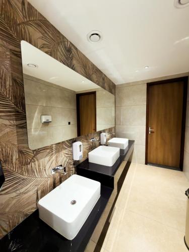 a bathroom with three sinks and a large mirror at Dwaraka INN in Arīkkod