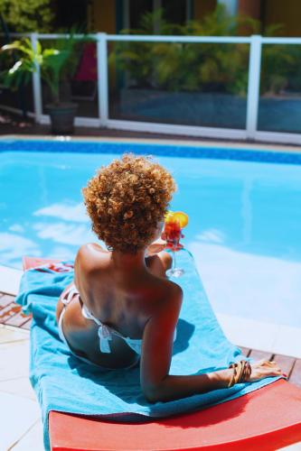 a woman sitting on a raft next to a swimming pool at Hôtel les Bougainvilliers in Saint-Gilles-les-Bains