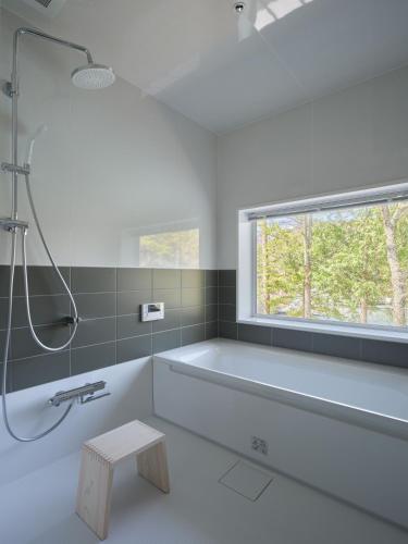 a white bathroom with a tub and a window at Hotel Miyam Matsubarako in Yanaike