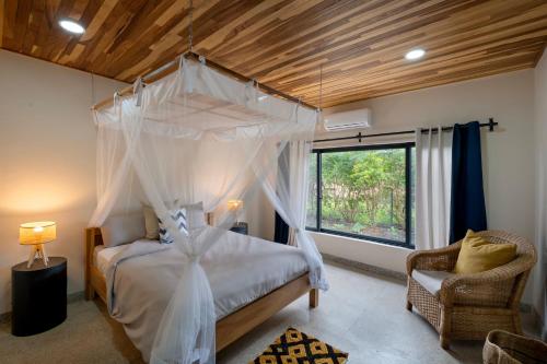 a bedroom with a canopy bed and a chair at Zambezi Drift Inn in Livingstone