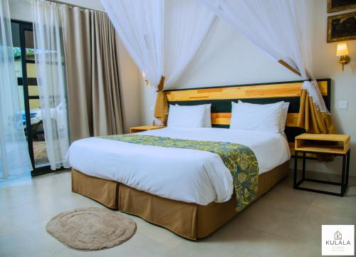 a bedroom with a large bed and a large window at Kulala Stays Lodge in Livingstone
