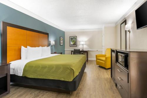 a hotel room with a bed and a yellow chair at Quality Inn & Suites North Charleston - Ashley Phosphate in Charleston