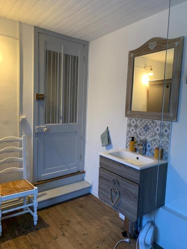 a bathroom with a sink and a mirror and a door at Maison cocooning in Hazebrouck