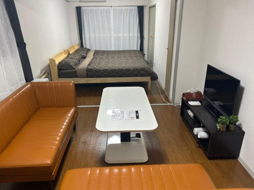 a small room with a bed and a couch and a table at KIYAZA Higashi Sapporo in Sapporo