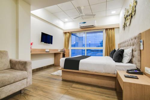 a bedroom with a bed and a couch and a window at Townhouse Oak PTC Indore Junction in Indore