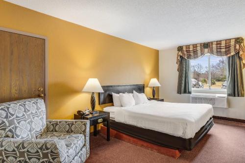 a hotel room with a bed and a chair at Econo Lodge Whitehall near Michigan's Adventure in Whitehall