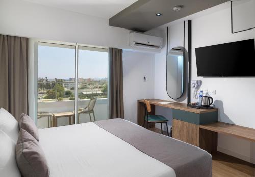 a hotel room with a bed and a desk with a television at Pefkos City Hotel in Limassol