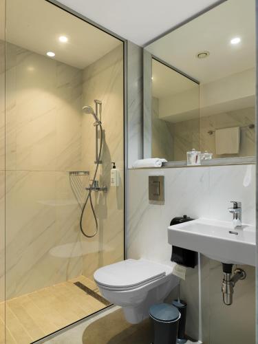 a bathroom with a shower and a toilet and a sink at Pefkos City Hotel in Limassol
