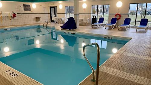 a swimming pool with blue chairs and tables in a building at Holiday Inn Express and Suites Detroit North-Troy by IHG in Troy