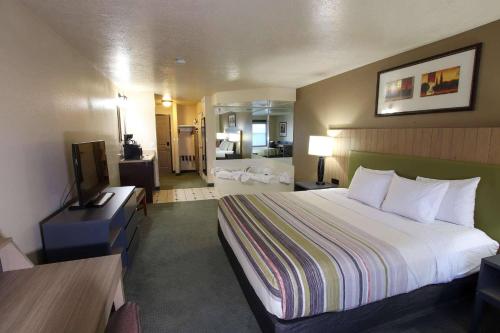 a hotel room with a bed and a bathroom at Country Inn & Suites by Radisson, West Valley City, UT in West Valley City