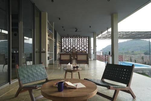 a living room with two chairs and a table and a table at SaffronStays Villa Rohi in Udaipur