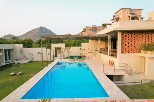 a swimming pool in the backyard of a house at SaffronStays Villa Rohi in Udaipur