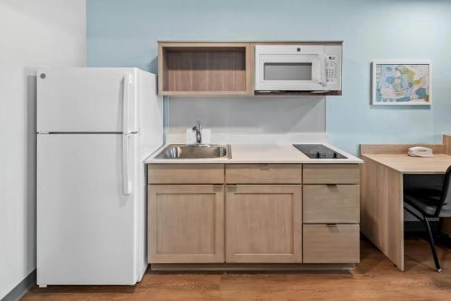 a kitchen with a white refrigerator and a sink at WoodSpring Suites Santee - San Diego Northeast in Santee