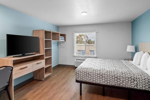 a bedroom with a bed and a flat screen tv at WoodSpring Suites Santee - San Diego Northeast in Santee