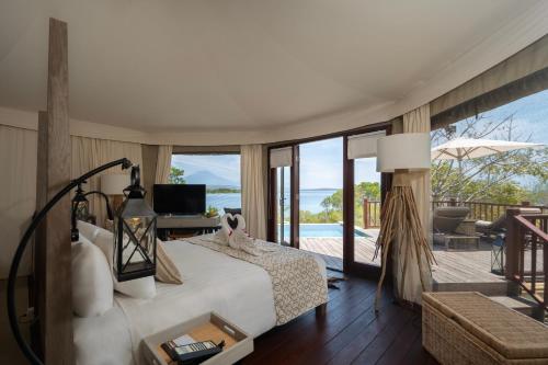 a bedroom with a bed and a view of the ocean at Menjangan Dynasty Resort in Banyuwedang
