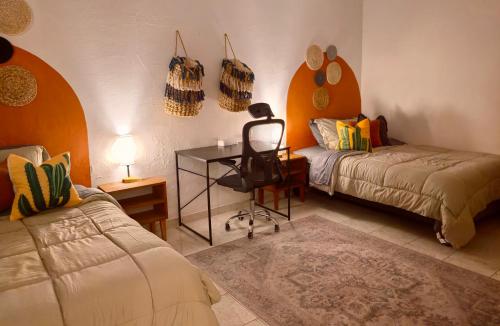 a bedroom with two beds and a desk and a chair at Casa completa en Jalatlaco con cocina equipada y parking hasta 7 huéspedes in Oaxaca City
