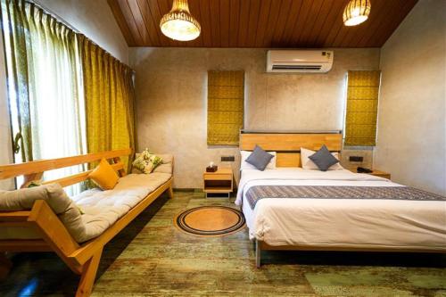 a bedroom with two beds and a couch in it at Cape Nirvana, Backwater & Pool villa in Lavasa