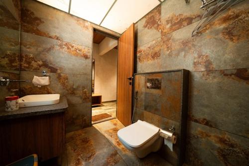 a dirty bathroom with a toilet and a sink at Cape Nirvana, Backwater & Pool villa in Lavasa