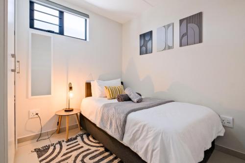 a white bedroom with a bed and a window at SoftPod Loft in Prime Location Fourways in Sandton