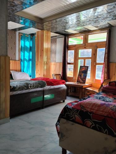 a bedroom with two beds and a table and windows at Paradise Homestay Tosh in Tosh