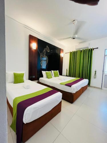 two beds in a room with green curtains at Seaport Negombo in Negombo