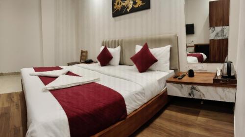 a bedroom with a large bed with red and white pillows at Hotel 7heaven in Kānpur