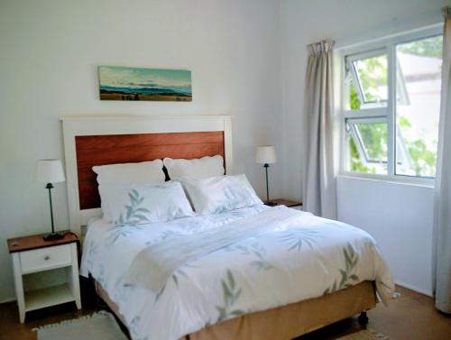 a bedroom with a bed with white sheets and a window at Sani's Rest in Himeville