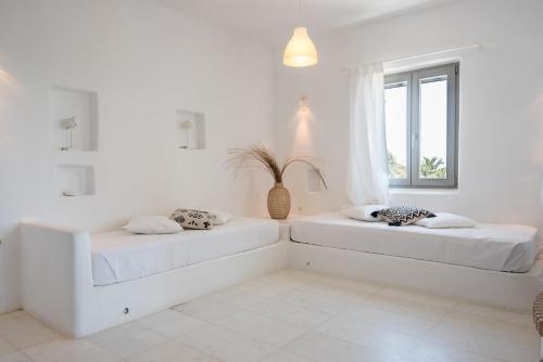 two beds in a white room with a window at Aeraki Villas in Santa Maria