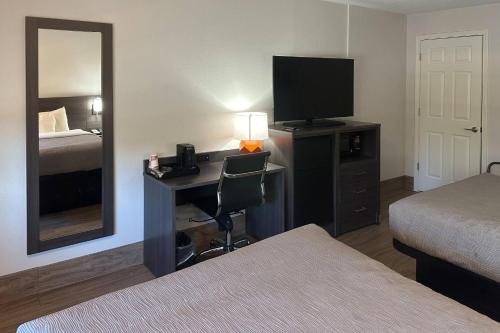 a hotel room with a desk with a television and a bed at Quality Inn Forsyth near GA Public Safety Training Center in Forsyth