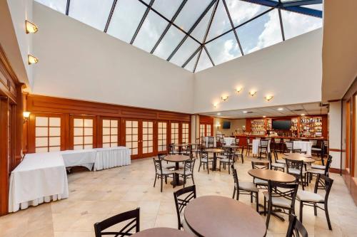 a dining room with tables and chairs and a large skylight at Clarion Hotel & Conference Center Toms River in Toms River