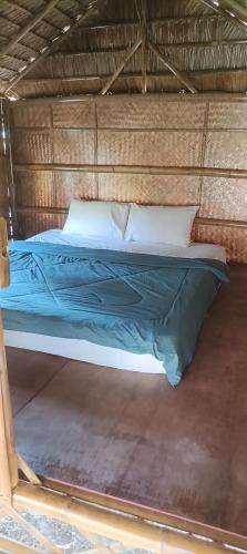 a bed with blue sheets and pillows in a room at in the palm hut in Phra Ae beach
