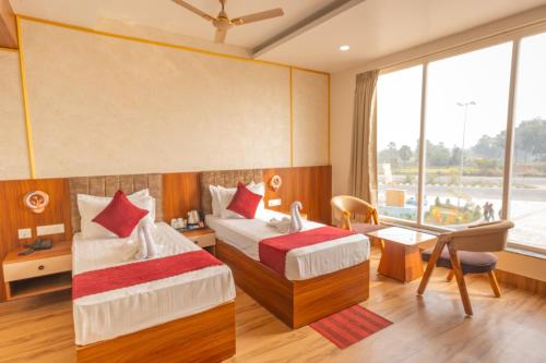 a hotel room with two beds and a desk and a window at Hotel Annapurna The Luxurious in Nalanda