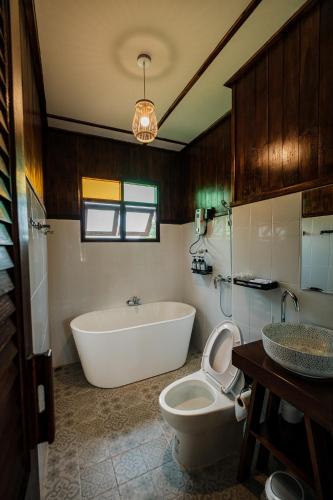 a bathroom with a tub and a toilet and a sink at Shine Villa Sukhothai in Sukhothai