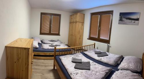a bedroom with two beds and a desk and windows at Apartmány TAS in Jablonec nad Jizerou
