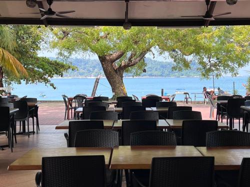 a restaurant with tables and chairs and a view of the water at Pangkor Sandy Beach Resort in Pangkor