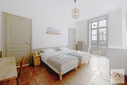 two beds in a white room with a window at L'Historique in Rennes