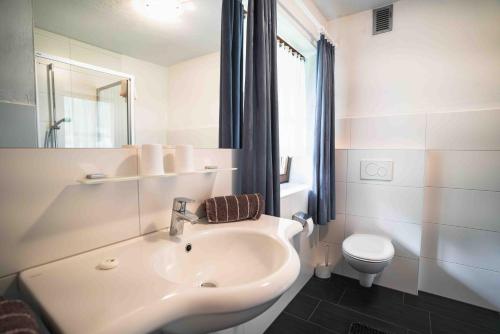a white bathroom with a sink and a toilet at HAUS Lampacher in Ganda di Martello