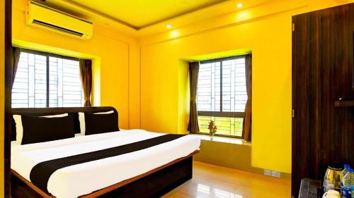 a yellow bedroom with a large bed with two windows at Downtown Ecoview Inn in Pānchuria