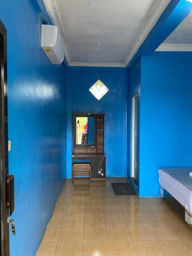 a blue room with a tv and a blue wall at Hotel Carollina Syariah in Girijati