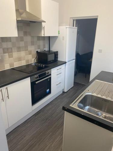 a kitchen with white cabinets and a stove and a sink at Beresford Guest House in Stoke on Trent