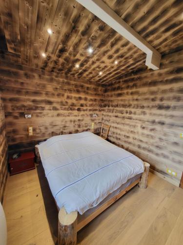a bed in a room with a wooden wall at Chalet d'alpage avec vue incroyable in Saint-Gervais-les-Bains