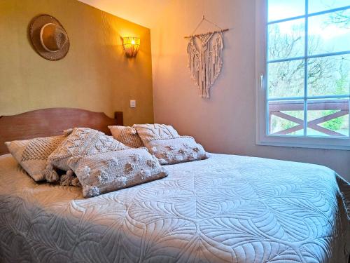 a bedroom with a bed with pillows and a window at Maison 3 chambres - 6-8 personnes - piscine chauffée - jacuzzi - internet - parking - Idéal familles & pros in Monflanquin