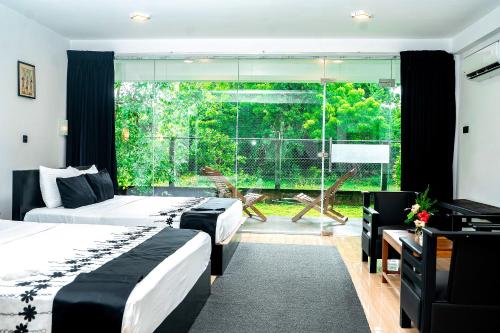 a bedroom with two beds and a large window at Forest Dew Udawalawa in Udawalawe
