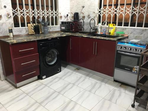 kuchnia z kuchenką i pralką w obiekcie EMA Apartment w mieście Kokrobite