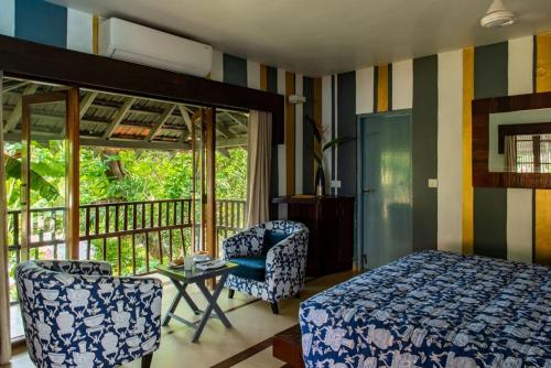 a bedroom with a bed and a chair and a balcony at Casa Vagator in Vagator